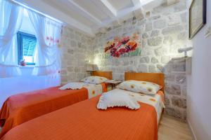 1 dormitorio con 2 camas y pared de piedra en Studio Stradun, en Dubrovnik