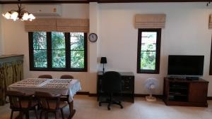 Una sala de estar con una mesa y sillas y un televisor. en Periwinkle Villa, en Ko Chang