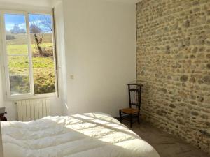 1 dormitorio con pared de ladrillo, cama y ventana en Domaine Lacay, en Beyrie-en-Béarn