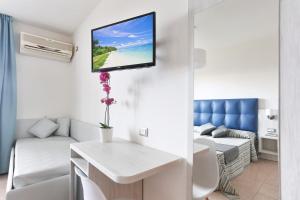 a living room with a couch and a tv on a wall at Hotel Nuovo Tirreno in Lido di Camaiore