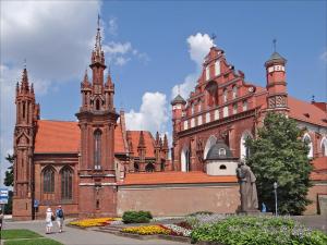 a large brick building with a statue in front of it at Cozy Apt in the Heart of Old Town in Vilnius