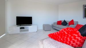 een woonkamer met een bank met een rood hartkussen bij Explorer Cove Unit 6 31 Kennedy Pde in Caloundra