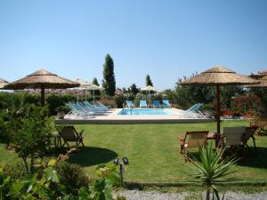 un patio con sillas y sombrillas y una piscina en Caviro, en Moúdhros