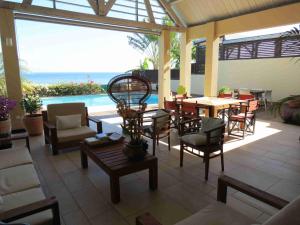 a patio with a table and chairs and a pool at Villa 'Florence' avec longue piscine et vue mer panoramique in Saint-Gilles les Bains