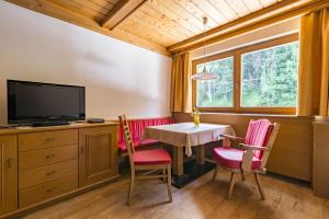 una sala da pranzo con tavolo, sedie e TV di Arina Apartments a Samnaun