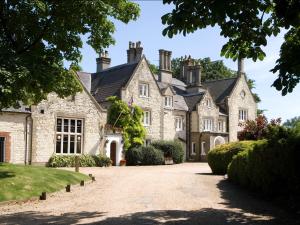 a large stone house with a driveway at Langrish House in Petersfield