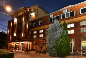 un grand bâtiment en briques avec un arbre devant lui dans l'établissement Garni Hotel Garson-Lux NS, à Novi Sad