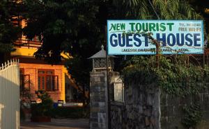 un nuevo cartel de hostal turístico frente a una casa en New Tourist Guest House en Pokhara