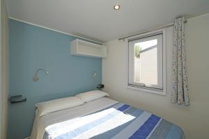 a small bedroom with a bed and a window at Butterfly Camping Village in Peschiera del Garda