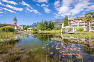 a pond in front of a hotel with a building at Hotel Weingarten in Appiano sulla Strada del Vino