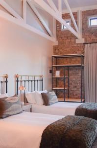 una camera con due letti e un muro di mattoni di Figberry Guestrooms a Bloemfontein