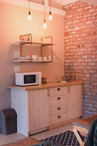 uma cozinha com um micro-ondas num balcão com uma parede de tijolos em Figberry Guestrooms em Bloemfontein