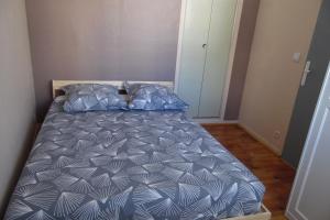 Schlafzimmer mit einem Bett mit einer blauen und weißen Bettdecke in der Unterkunft Appartement Paisible in Briançon