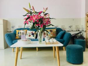gau homestay في توي هوا: غرفة معيشة مع أريكة زرقاء وطاولة مع زهور