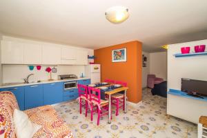 una cucina con armadi blu e un tavolo con sedie rosse di Ampio monolocale al mare nel Salento Ionio m604 a Torre Vado