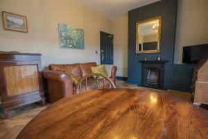 sala de estar con mesa, sofá y chimenea en The Little St Apartment, en Macclesfield