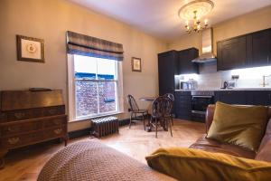 cocina y sala de estar con sofá y mesa en The Little St Apartment, en Macclesfield