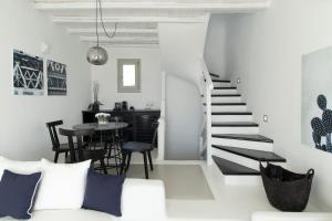 a white living room with a staircase and a table at Nimbus Mykonos in Agios Stefanos