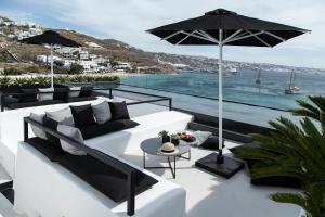 a patio with a white couch and an umbrella at Nimbus Mykonos in Agios Stefanos