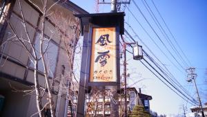 un cartello sul lato di un edificio accanto a un albero di Tabist Kazeyuki a Takayama