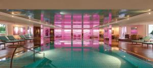 a swimming pool in a building with pink walls at GRAND ELYSEE Hamburg in Hamburg