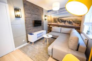 - un salon avec un canapé et une télévision dans l'établissement Apartamenty Sun & Snow Centrum Cicha, à Krynica-Zdrój