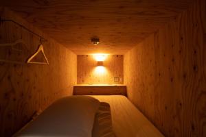 a small room with a bed in a wooden wall at Guesthouse Akicafe Inn in Hiroshima