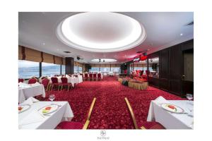 a dining room with white tables and red carpet at Ege Palas in İzmir