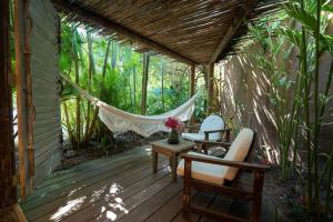 a porch with a hammock and chairs on a deck at Casa Angatu in Trancoso