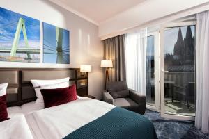 a hotel room with a bed and a chair and a window at Wyndham Köln in Cologne