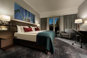 a hotel room with a bed and a chair and a desk at Wyndham Köln in Cologne