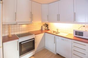cocina con armarios blancos, fregadero y microondas en Fjelltun 8-sengs en Trysil