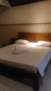 una camera da letto con letto, lenzuola e cuscini bianchi di Dewi Antara Homestay ad Ubud