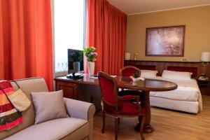 ミラノにあるホテル アルガのテーブルとベッドが備わるホテルルームです。
