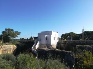 un edificio bianco posto sopra un muro di pietra di Le Case Di Tufo Riccio di mare a Favignana