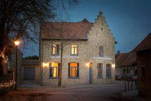 une ancienne maison en pierre avec des lumières devant elle dans l'établissement In den Paardenhandel te Lampernisse, à Dixmude