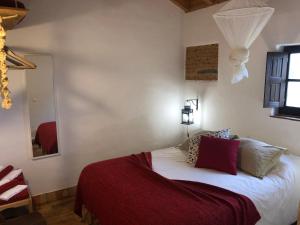 1 dormitorio con 1 cama con manta roja en Quinta das Beldroegas - Casas de Campo en São Teotónio