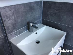 lavabo blanco en un baño con azulejos grises en Hotel Schurwald en Rechberghausen