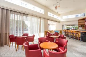 a waiting room with tables and red chairs at Irinna Hotel-Apartments in Faliraki