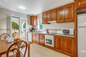 a kitchen with wooden cabinets and a table and a counter top at Villa Alicia in Cala Galdana