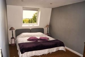 a bedroom with a bed with purple pillows and a window at Chambres d'Hôtes La Parenthèse in Wambrechies