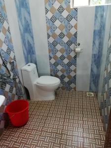 a bathroom with a toilet and a red bucket at kannur west beach homestay in Kannur