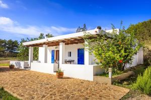 a small white house with a blue door at Finca Can Carlets in Cala Saona