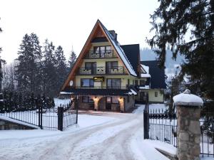 una casa con techo de gambrel en la nieve en Polakówka, en Poronin