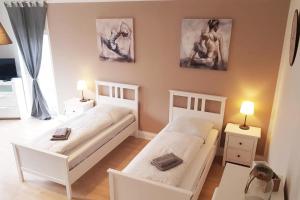 two beds in a room with two tables and two lamps at Cosy Apartment Neuss in Neuss