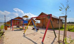 a playground with colorful equipment in front of a house at Domki u Małgosi in Rusinowo +4 photos