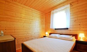 a bedroom with a bed in a wooden cabin at Domki u Małgosi in Rusinowo