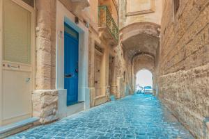 eine Gasse mit einer blauen Tür an einem Gebäude in der Unterkunft Gunpost Suite in Valletta