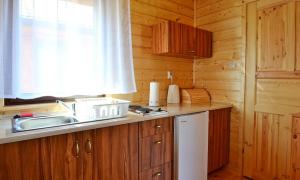 cocina con armarios de madera, fregadero y ventana en Domki u Małgosi, en Rusinowo