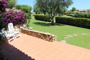 d'une terrasse avec 2 chaises blanches et un mur en pierre. dans l'établissement Appartamenti residence Vela Blu Golfo Aranci, à Marinella